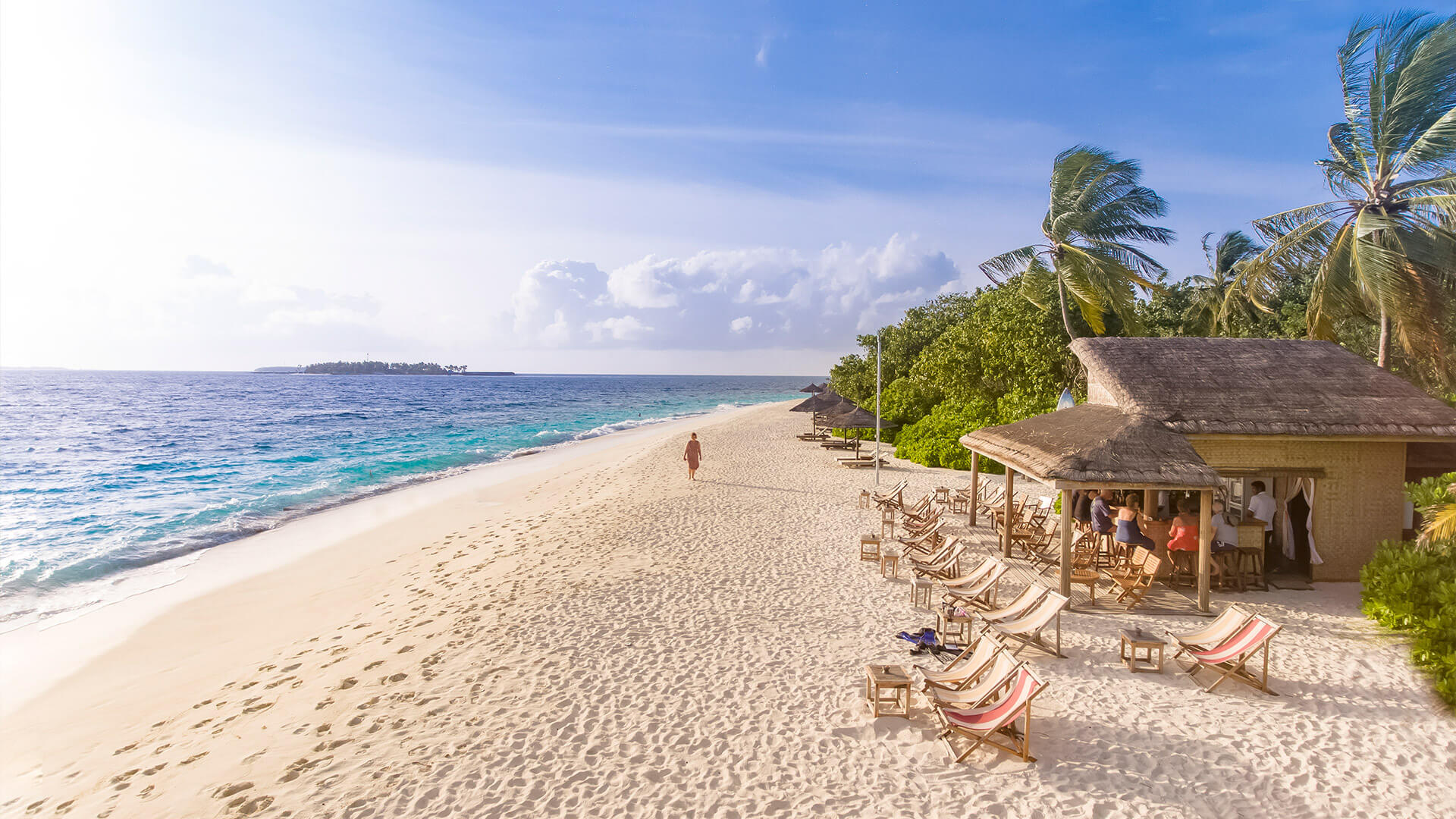 A girl walking on a white sand beach on Maldives Island