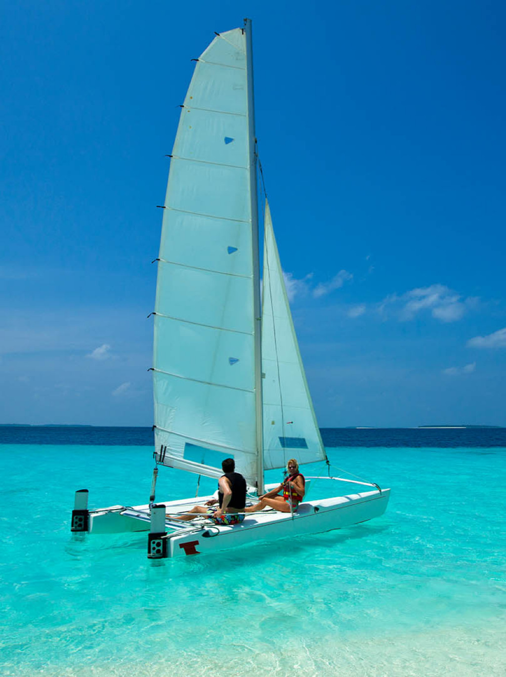 A couple sailing on a colorful catamaran on a beach at Maldives