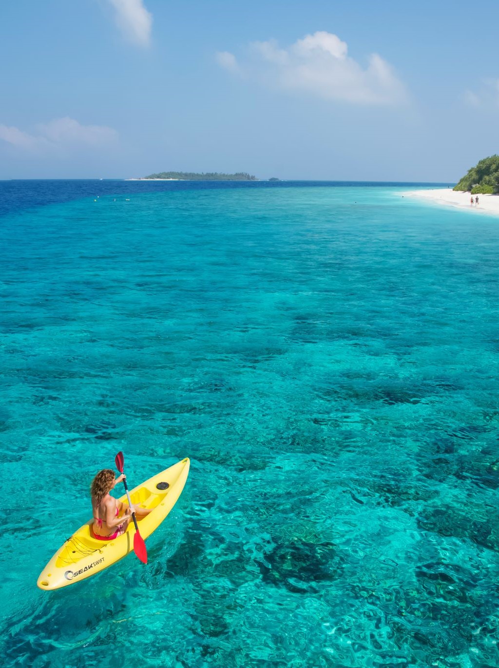 A woman in a canoe over water in the Maldives