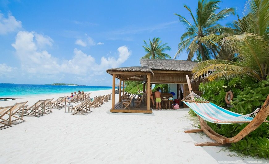 In-door sunset bar with sunbeds on the white sand beach at Maldives