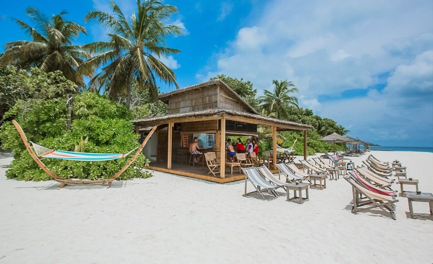 Overview of sunset bar with sunbeds at Reethi Beach Resort
