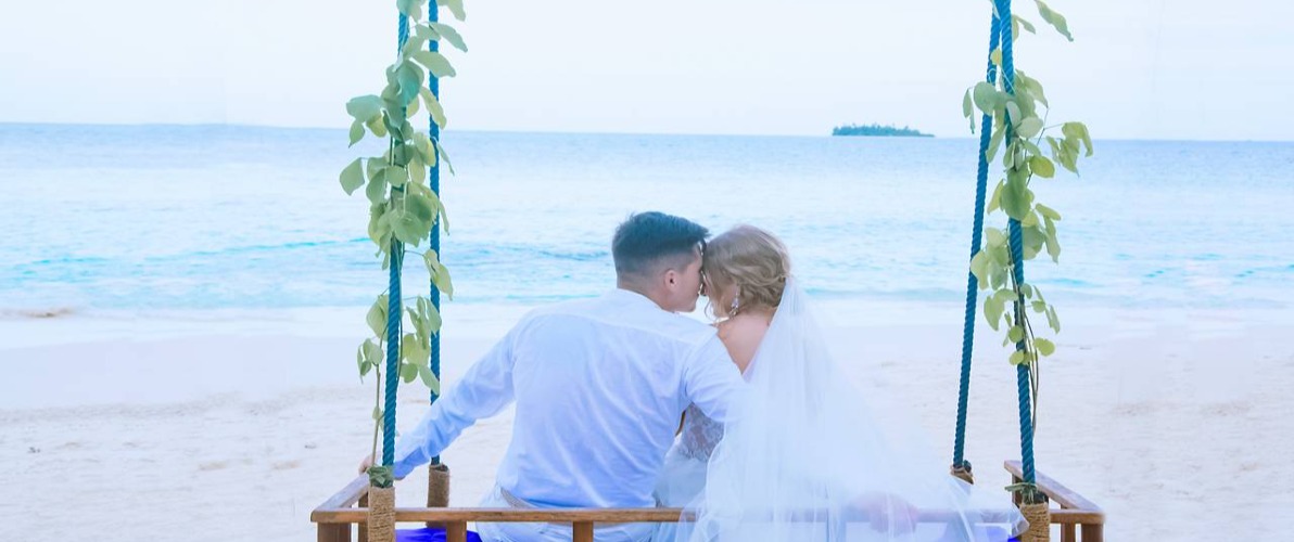 A married couple photo shoots on a Maldives beach.