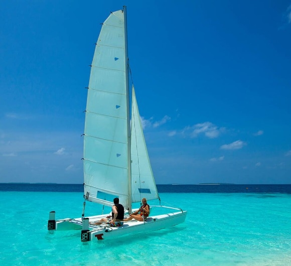 A couple sailing on a colorful catamaran on a beach at Maldives