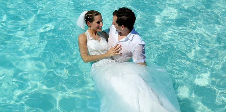 The groom holds the bride in his arms on beach photo shoot at Maldives